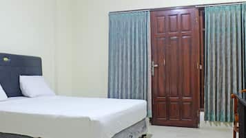 A bedroom with a bed, a wooden door, and curtains.