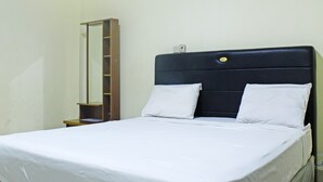 A bed with white bedding, a dark headboard, and a mirror on the wall. - Collection O 91517 Hotel Gajah Mada Soe (Soe)