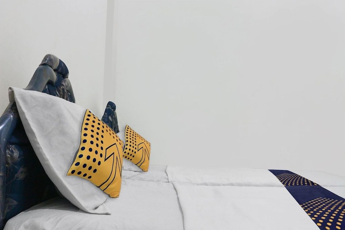 Un lit avec un drap blanc et deux oreillers à motifs jaunes.