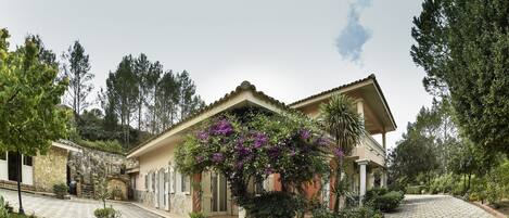 A Mediterranean-style villa with a tiled courtyard, stone walls, and lush greenery.