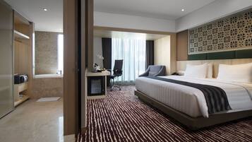 Una habitación de hotel con una cama grande, un escritorio, una silla y un baño.