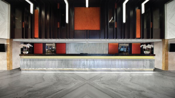 A reception area with a marble floor, a reception desk, and a large window. - Sovereign Bali Hotel (Tuban)