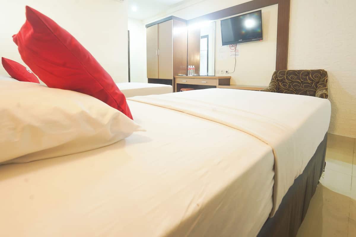 A hotel room with two beds, a desk, a chair, and a television on the wall.