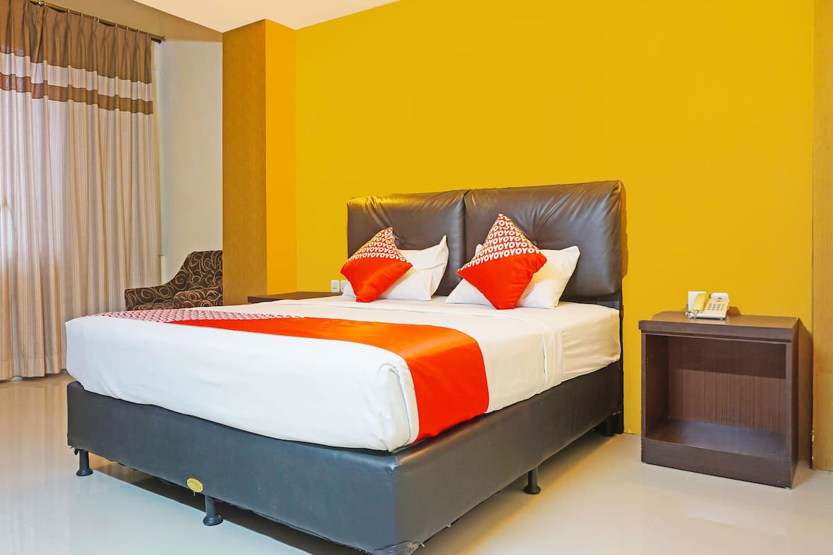 A hotel room with a bed, a nightstand, and a chair.