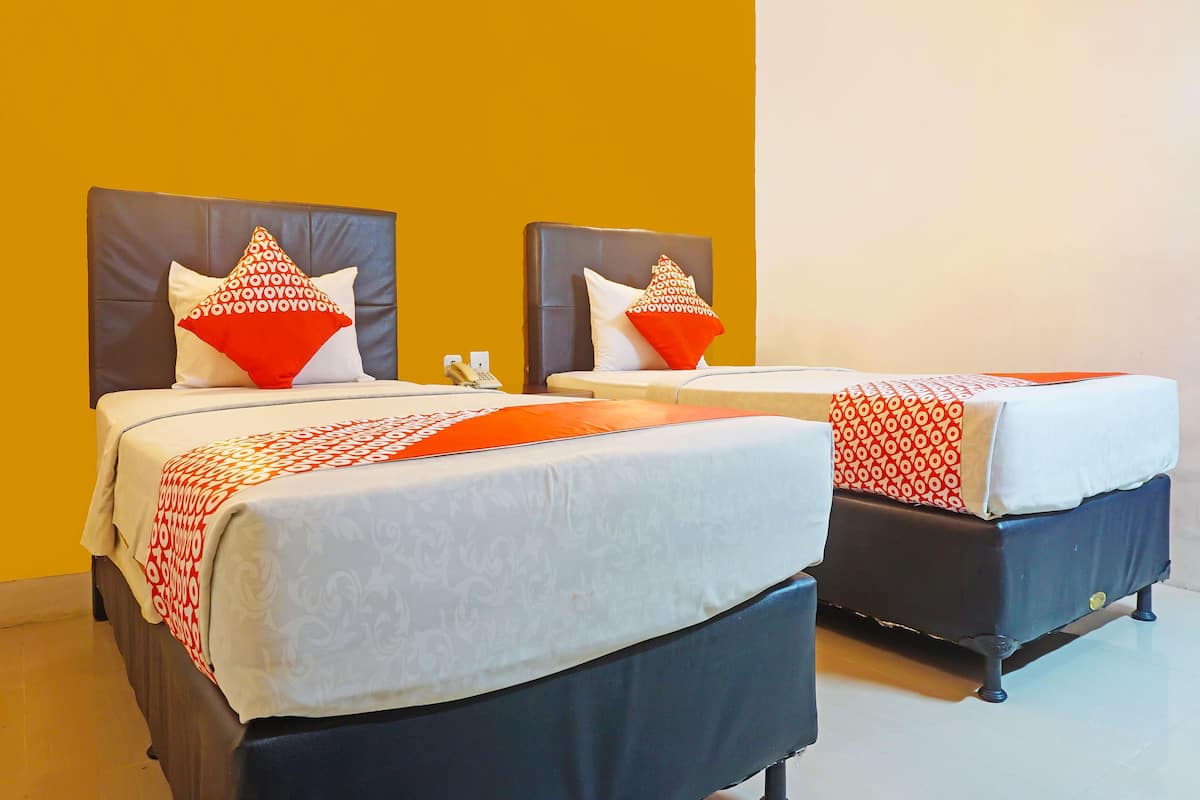 Two beds with headboards, a telephone, and a patterned bedspread.