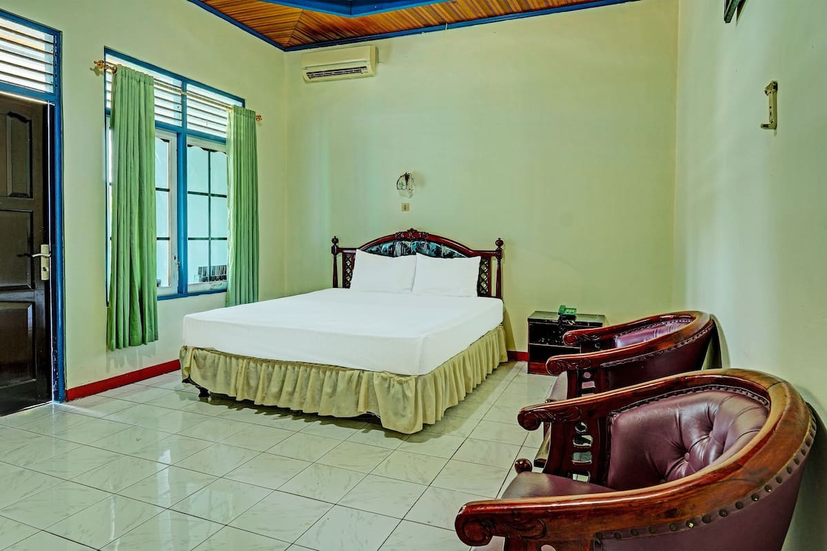 Une chambre à coucher avec un lit, une chaise, une table de chevet et une fenêtre avec des rideaux.