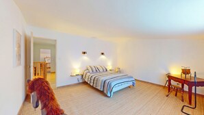 Une chambre à coucher avec un lit, des lampes de chevet, une chaise en bois et une petite table.