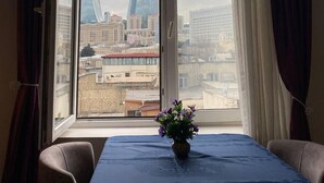 A room with a large window, a table with a blue tablecloth, and a potted plant. - Qız Qalası Hotel (Baku)
