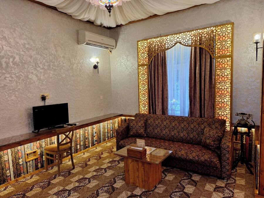 A living room with a patterned sofa, a wooden coffee table, a television, and a decorative wall panel.