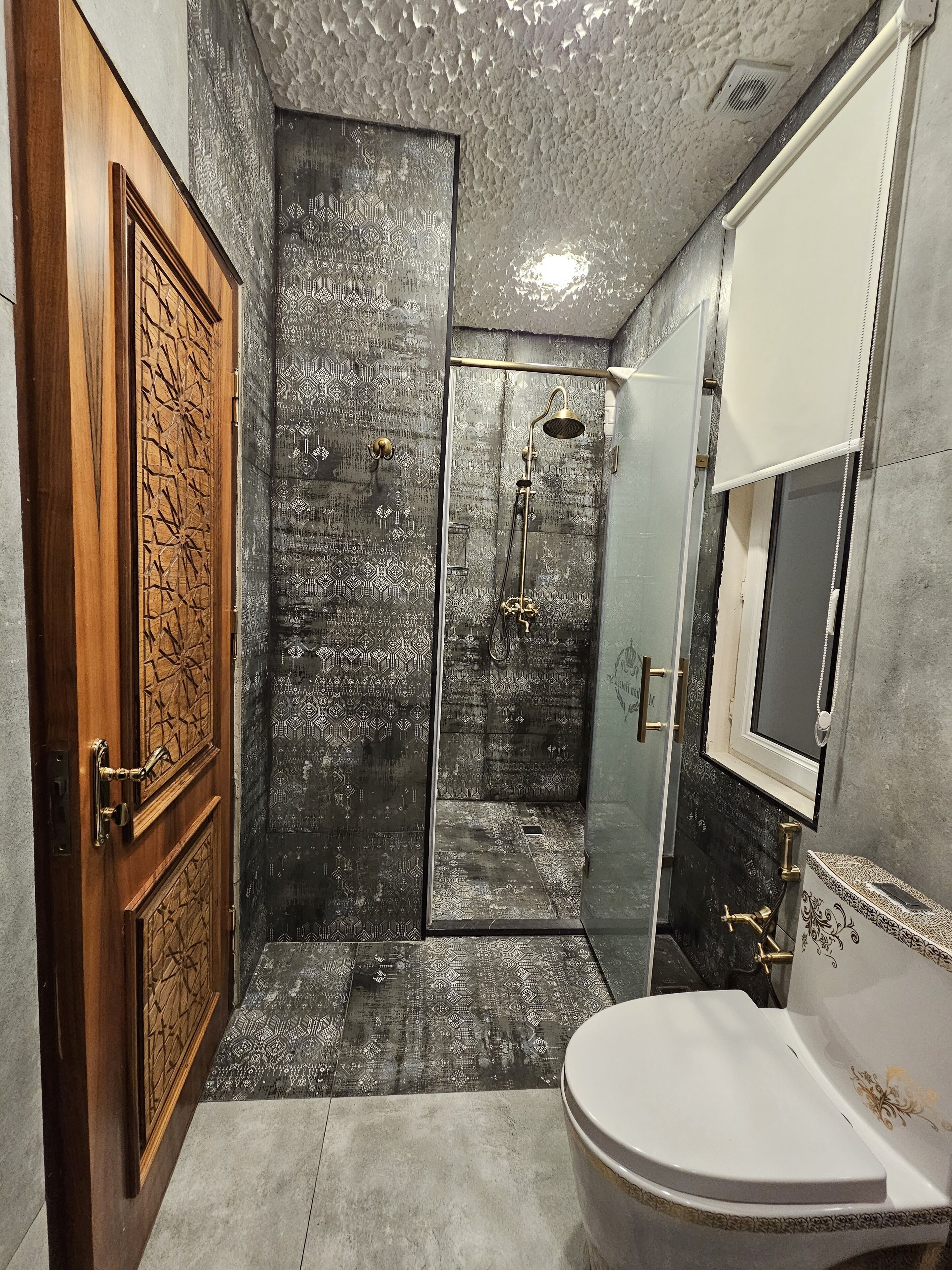 Un baño con ducha, inodoro y puerta de madera.