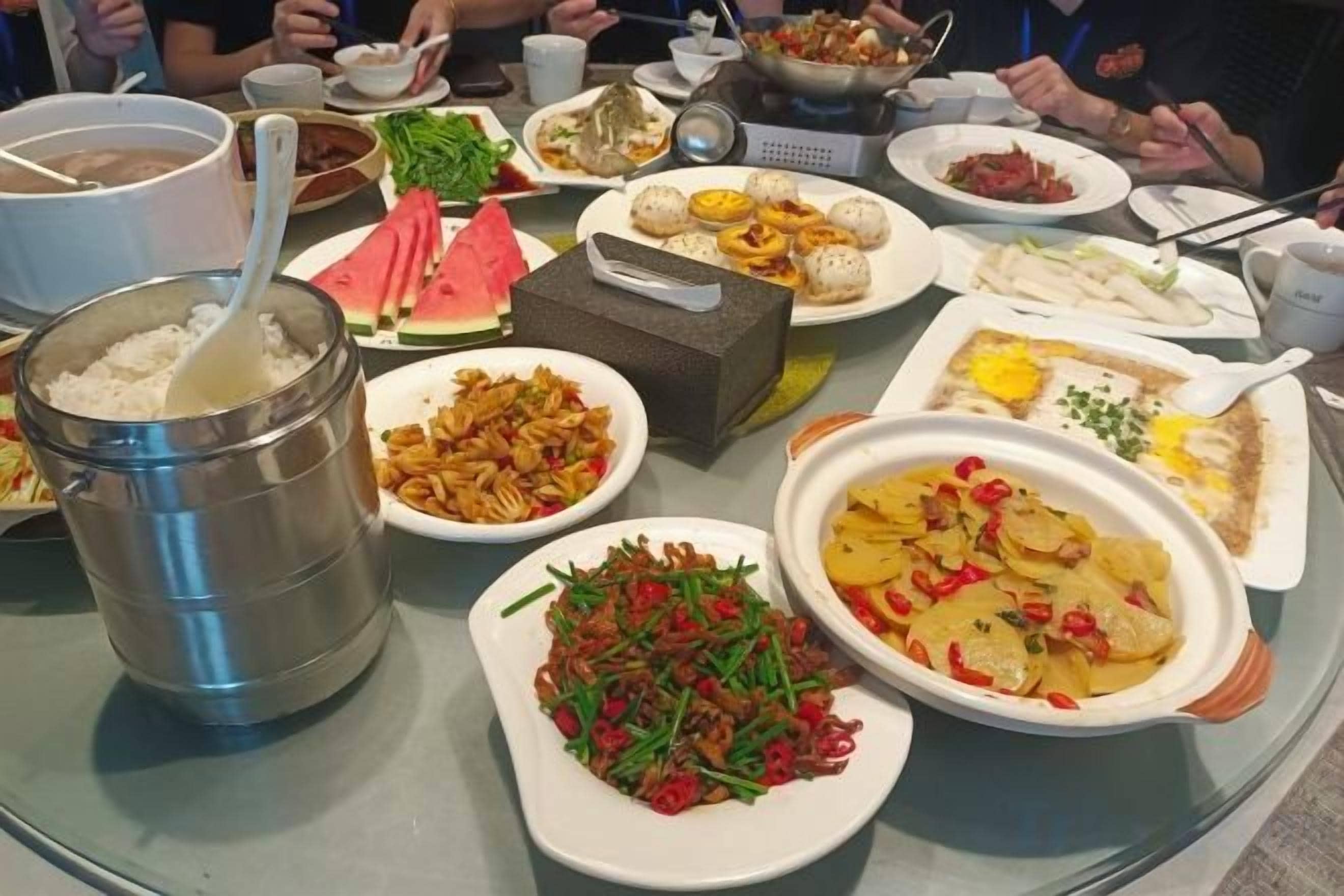 Une table sur laquelle se trouvent divers plats, notamment un récipient en métal, un bol de nouilles et une assiette de légumes.