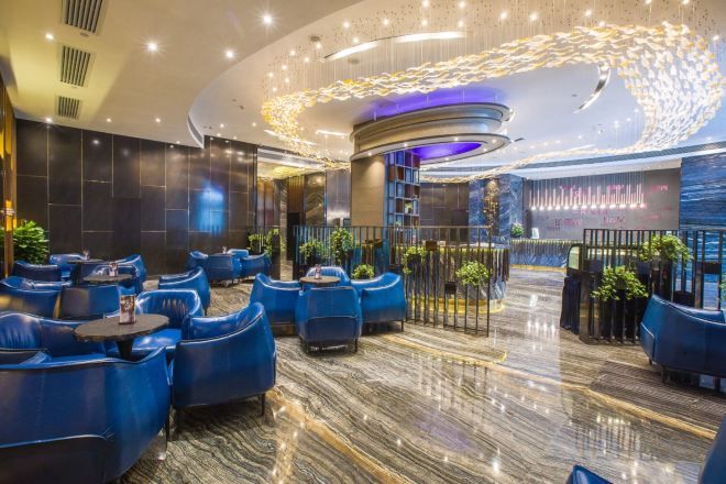 A modern hotel lobby with seating areas, a reception desk, and decorative lighting.