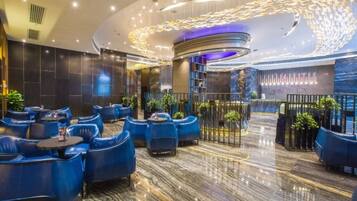 A modern hotel lobby with seating areas, a reception desk, and decorative lighting.