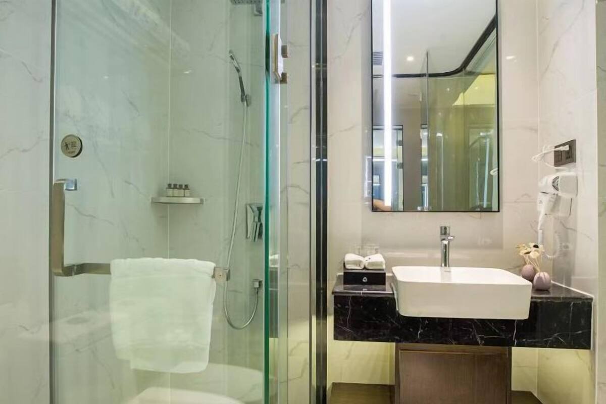 A modern bathroom with a glass-enclosed shower, a vanity with a sink, and a large mirror.