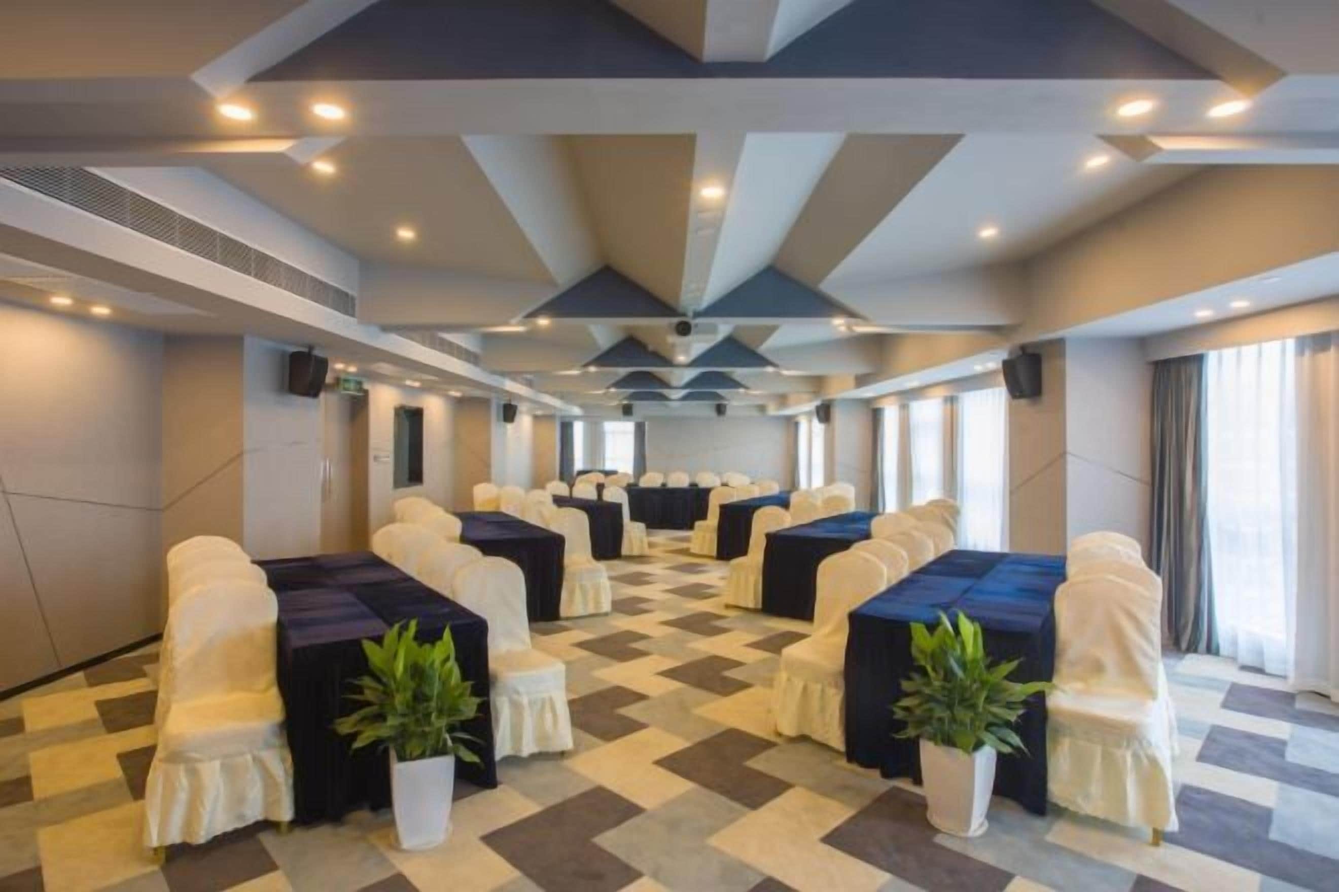 A conference room with a checkered floor, tables with blue tablecloths, and white chairs.