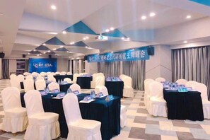 A conference room with rows of white chairs, tables with nameplates, and a banner with text. - Ruiman International Hotel (Changsha)