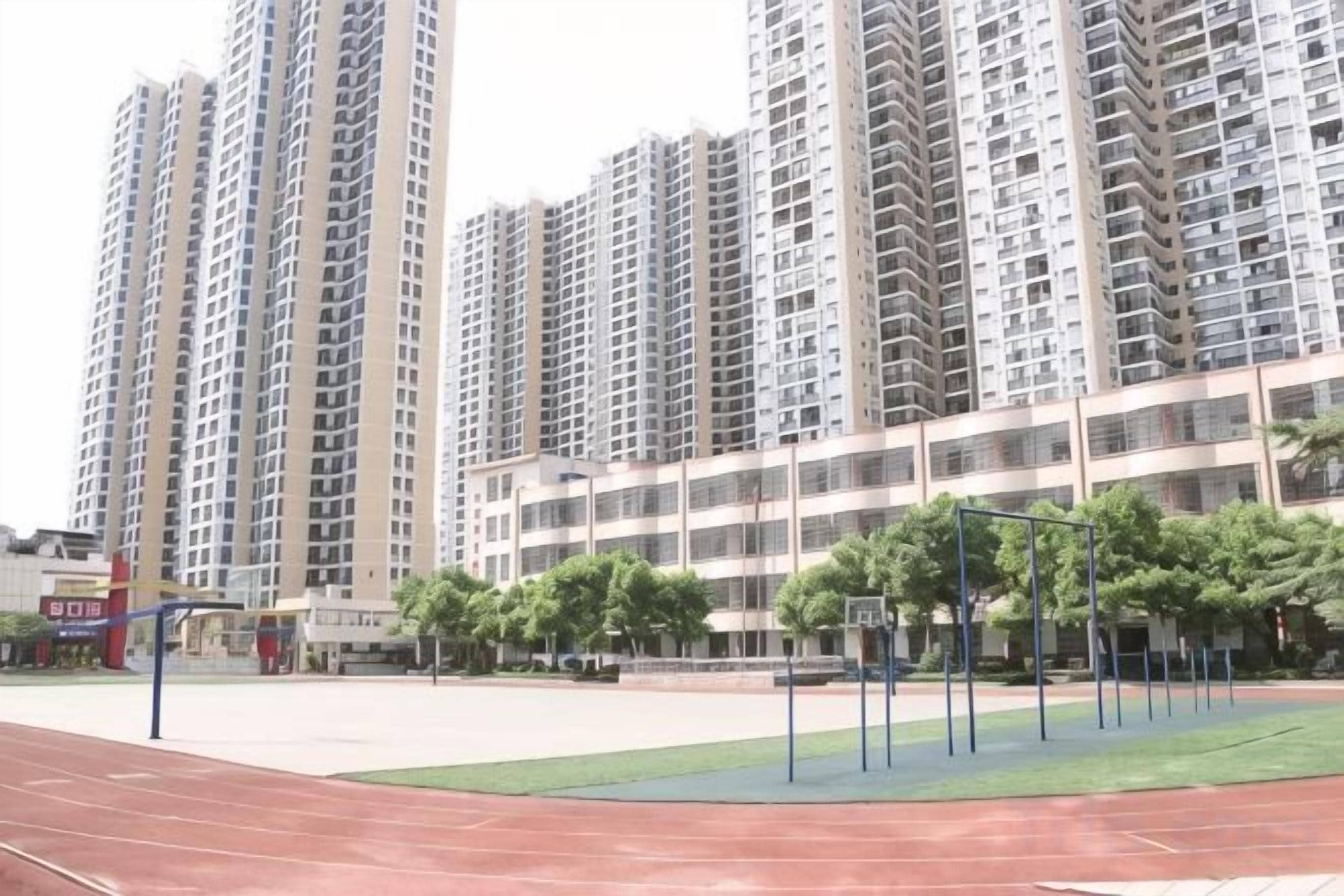 A residential building with multiple high-rise apartments, a sports court, and a small park area.