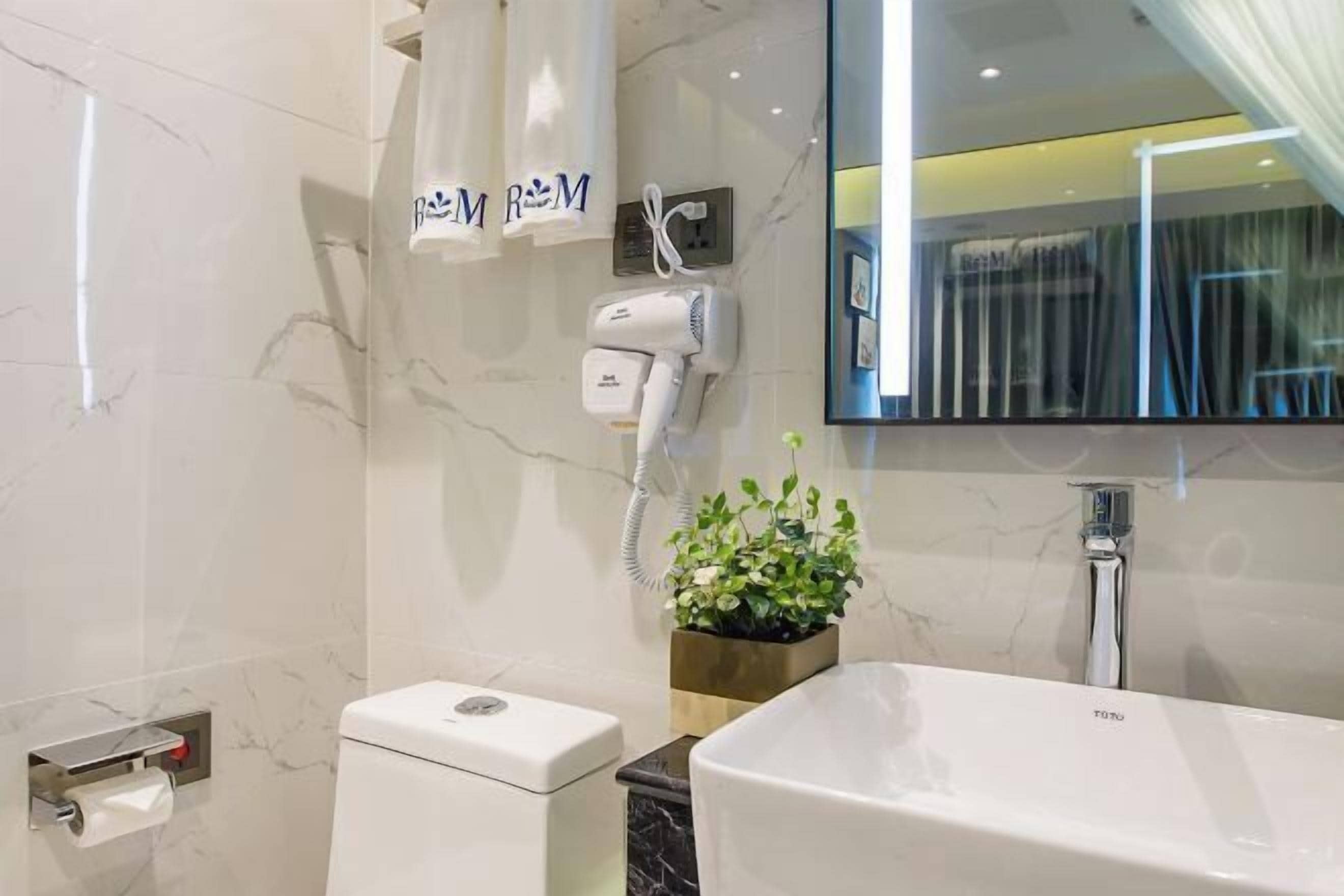 Une salle de bain moderne équipée de toilettes, d’un lavabo, d’un sèche-cheveux et d’un miroir.