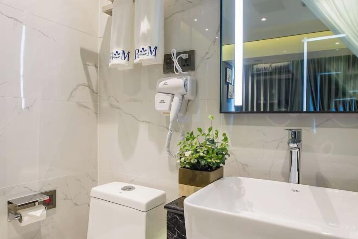 Un baño moderno con inodoro, lavabo, secador de pelo y espejo.