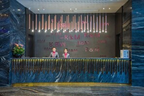 A reception desk with a marble wall and a neon sign. - Ruiman International Hotel (Changsha)