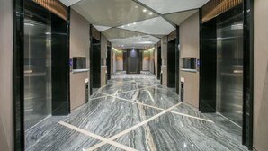 Un vestíbulo de ascensor moderno con suelo de mármol y puertas de cristal.