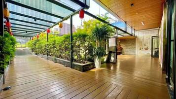 A covered walkway with wooden flooring, potted plants, and red lanterns.