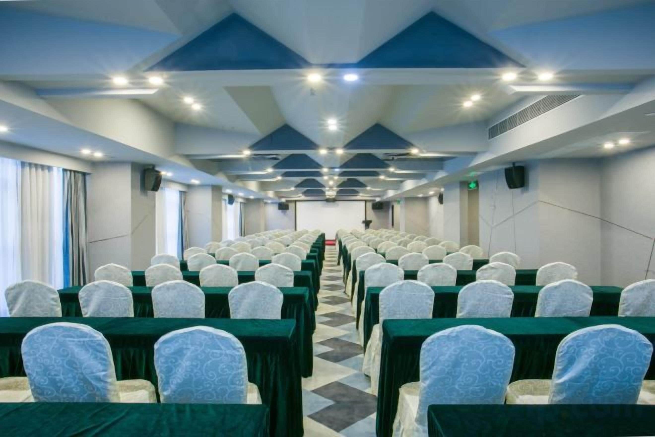 A conference room with rows of chairs, a stage at the front, and a long table.