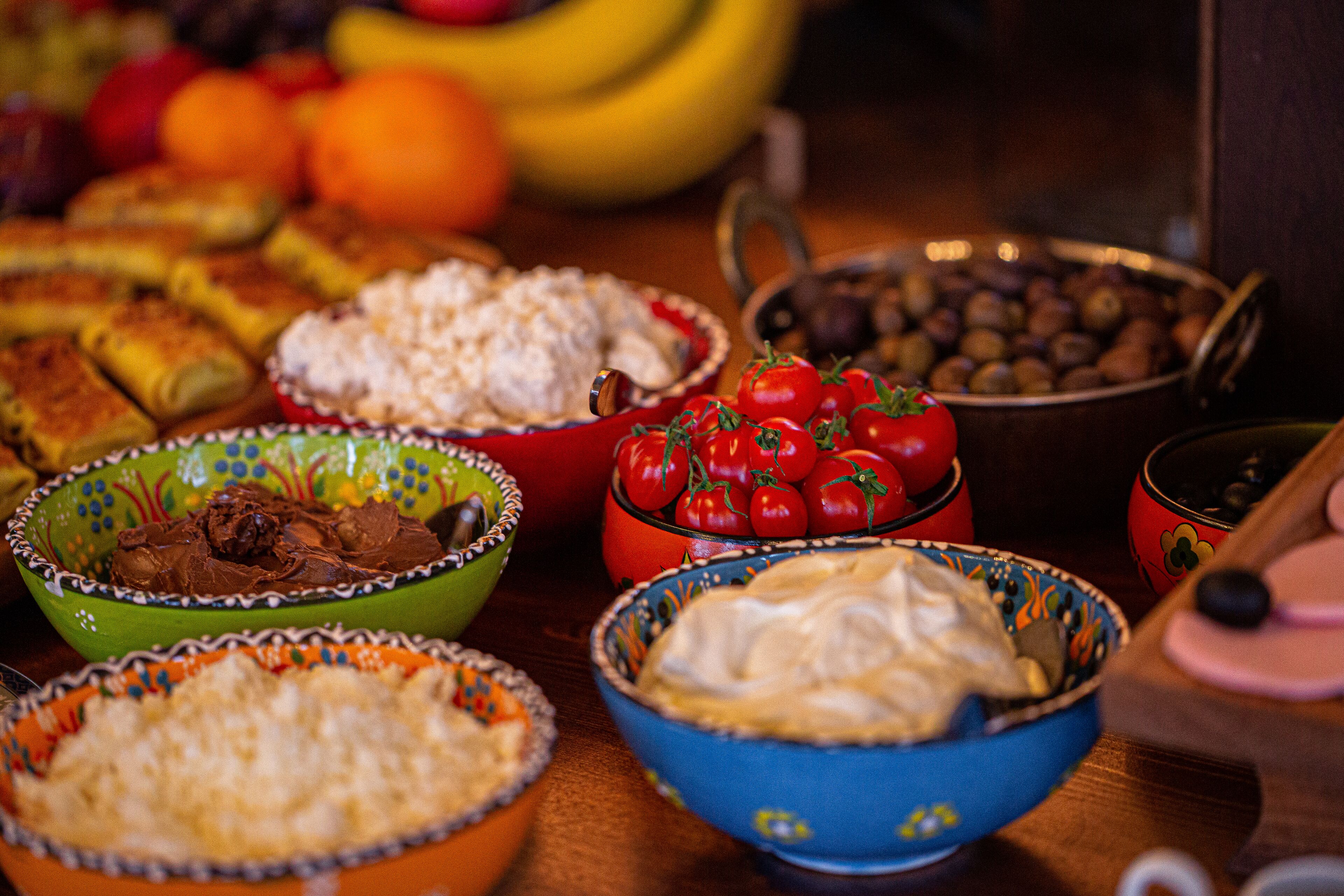 On peut voir une variété d’aliments sur une table en bois, notamment des bols de riz, des tomates et des olives.