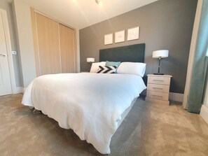 Cozy retreat with a large bed, bedside table, and wardrobe.