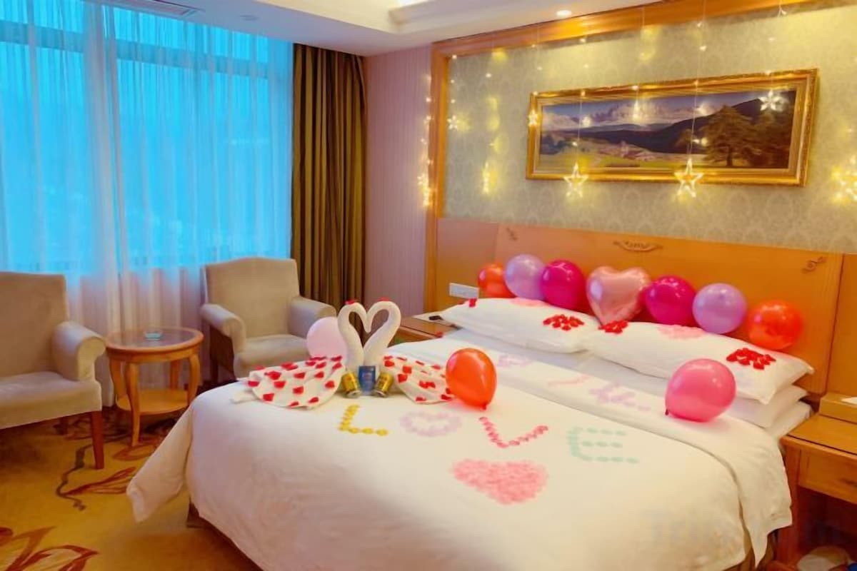 A hotel room with a bed, two armchairs, a small table, and a painting on the wall.