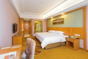 Una habitación de hotel con cama, mesita de noche, silla y televisor.