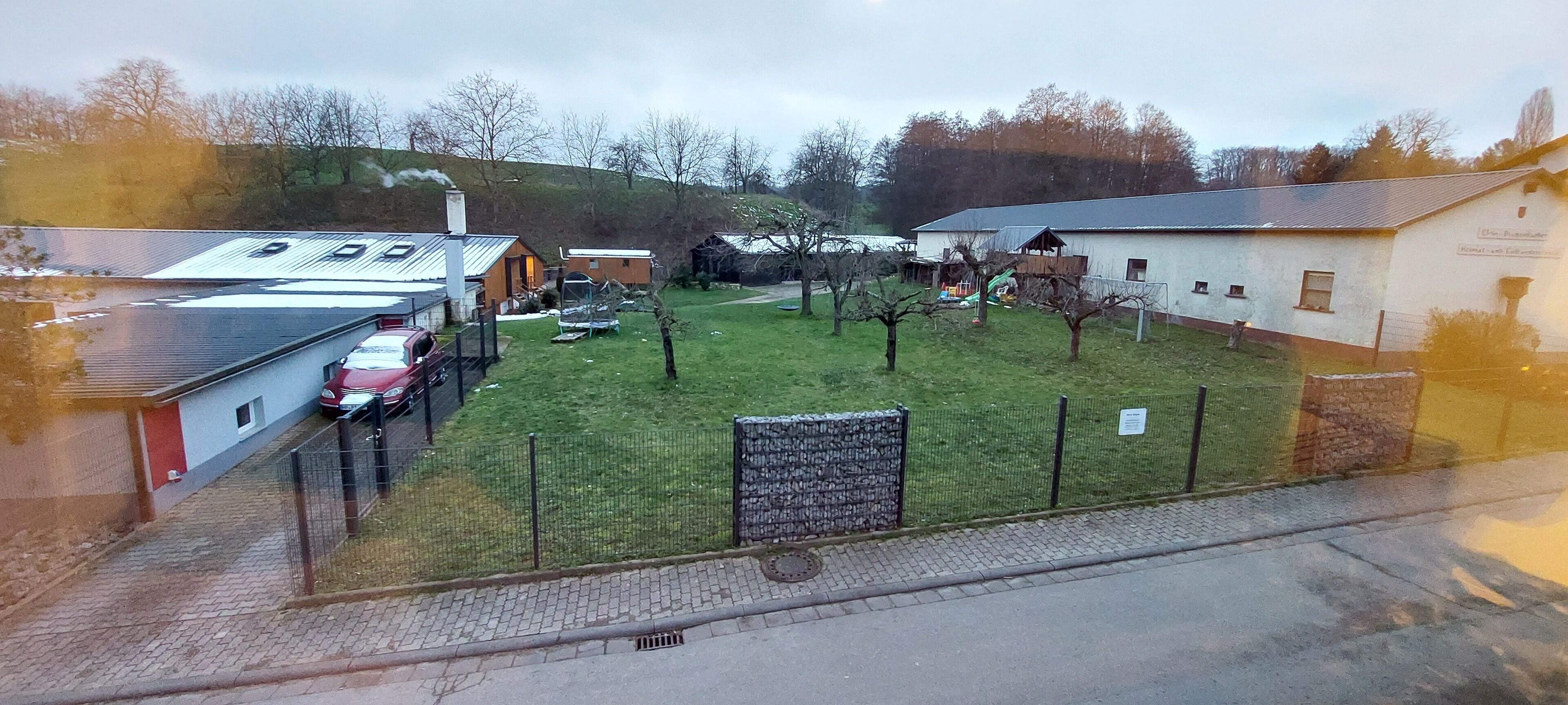 A parking lot with several cars, a grassy area with trees, and buildings with signage.