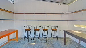 Ein Zimmer mit hoher Decke, vier Metall-Barhocker und zwei Holztische.