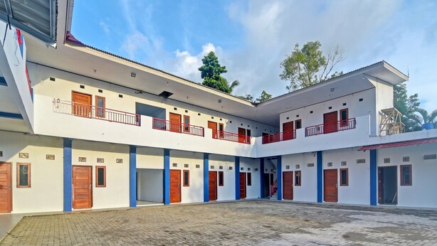 Ein mehrstöckiges Gebäude mit Innenhof, mit Balkonen und roten Geländern sowie Holztüren.