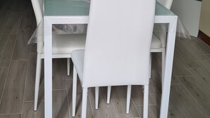 A dining area with a table and four chairs, a television mounted on the wall, and a small decorative item on the table. - Renovated two-bedroom apartment, parking space, by the sea. (Marina di Caronia)