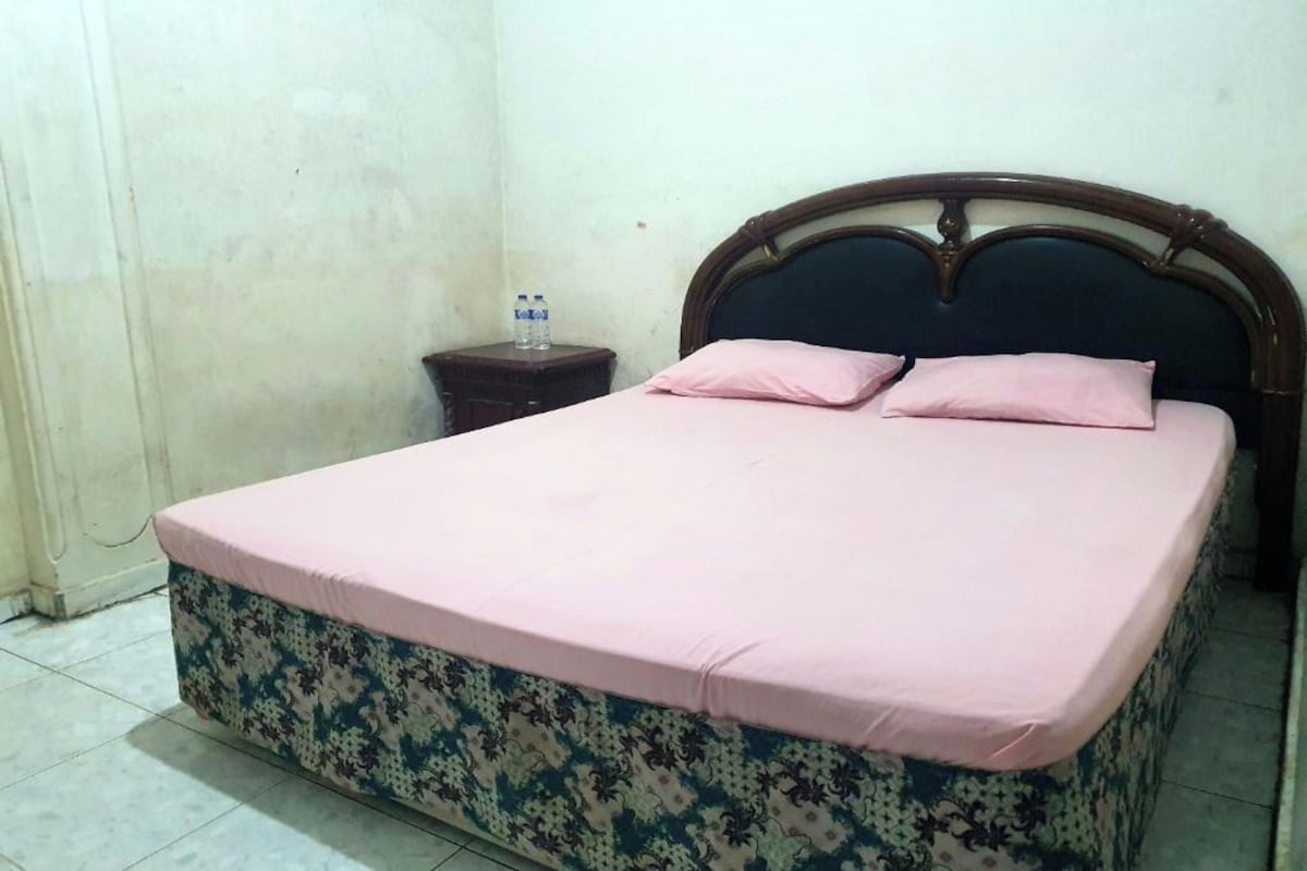 A single bed with a floral-patterned mattress and a wooden headboard.