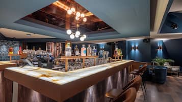 A modern bar with a marble countertop, wooden ceiling, and ambient lighting.