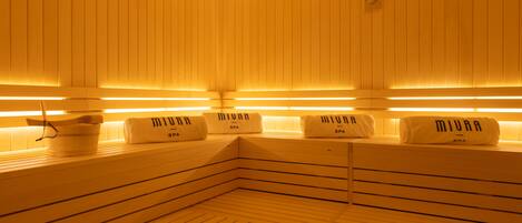 A sauna with wooden benches and benches labeled "MIURA SPA".