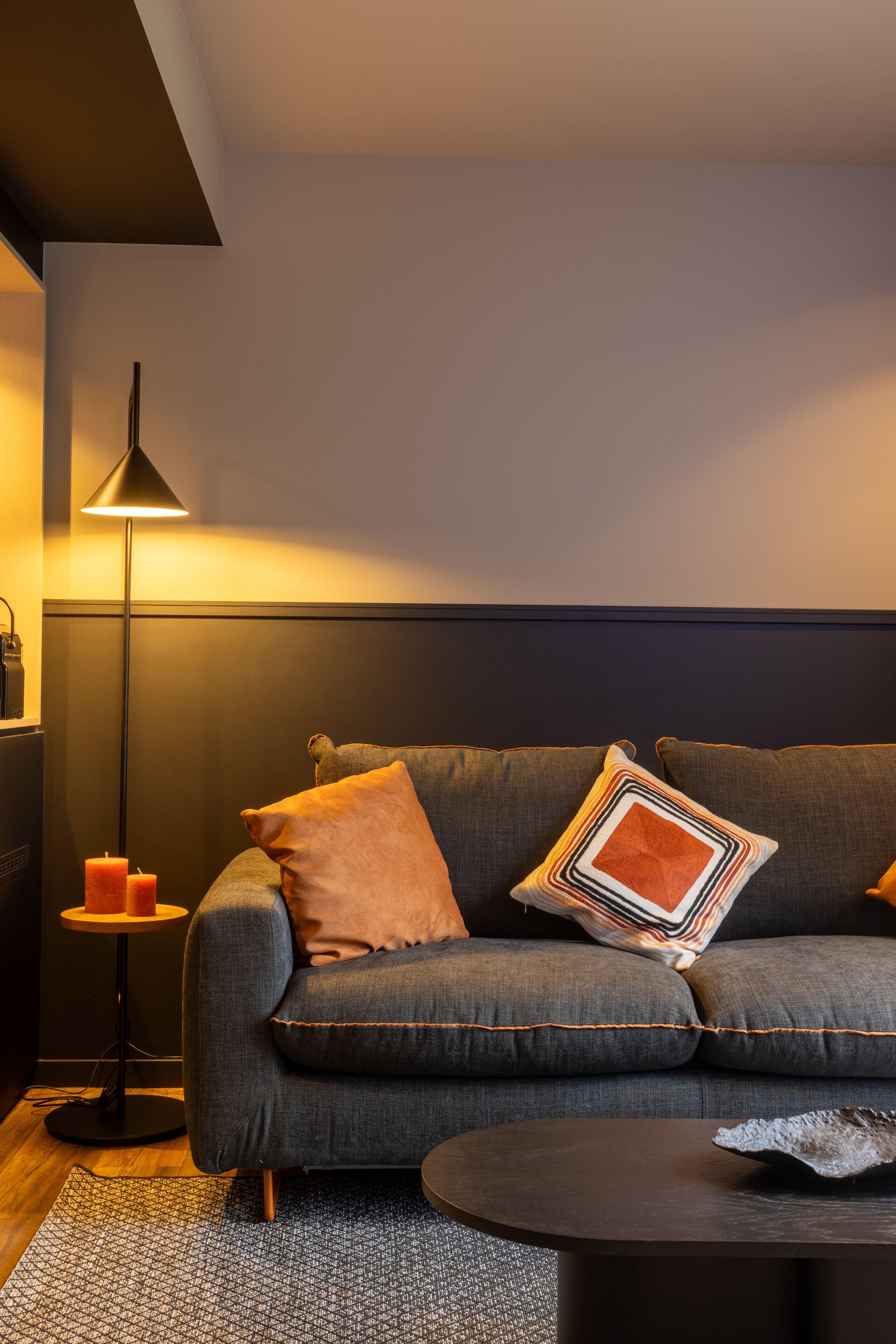 A modern living room with a grey sofa, a round coffee table, and a floor lamp.