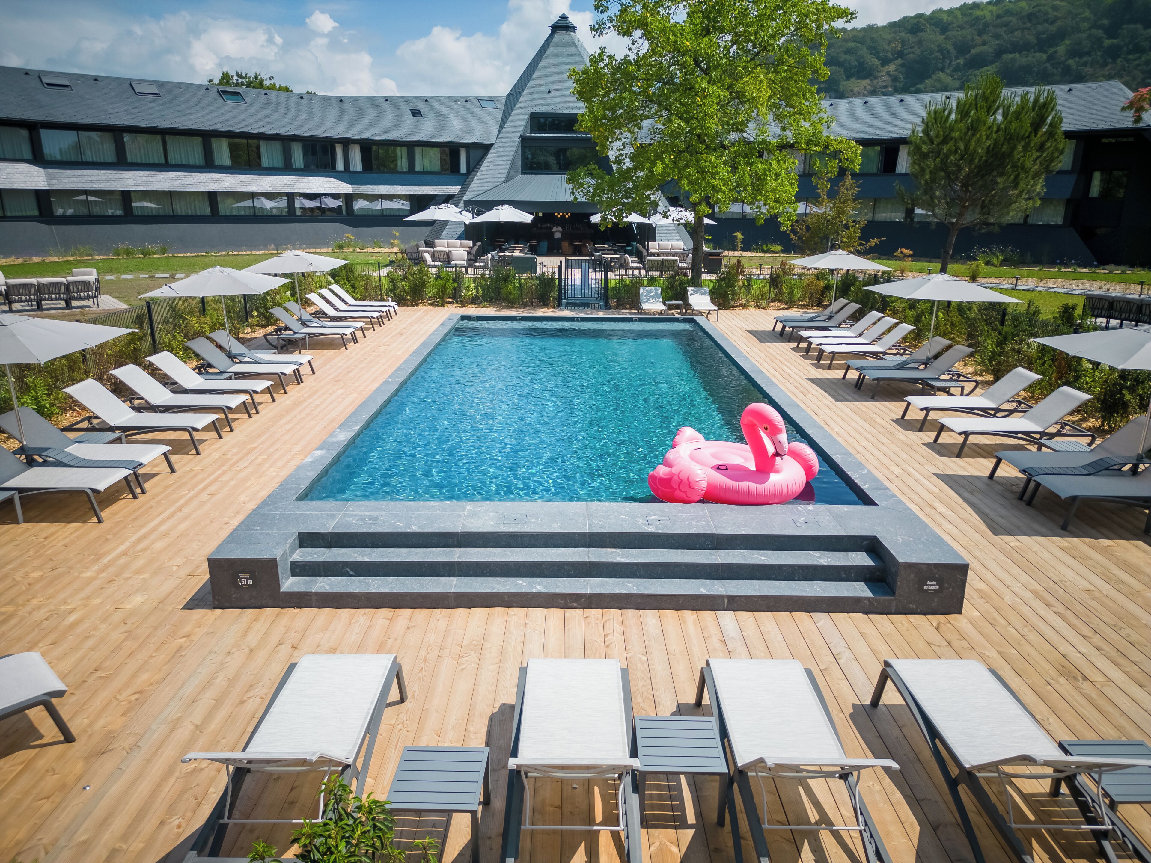 A swimming pool with lounge chairs and a pink flamingo float.