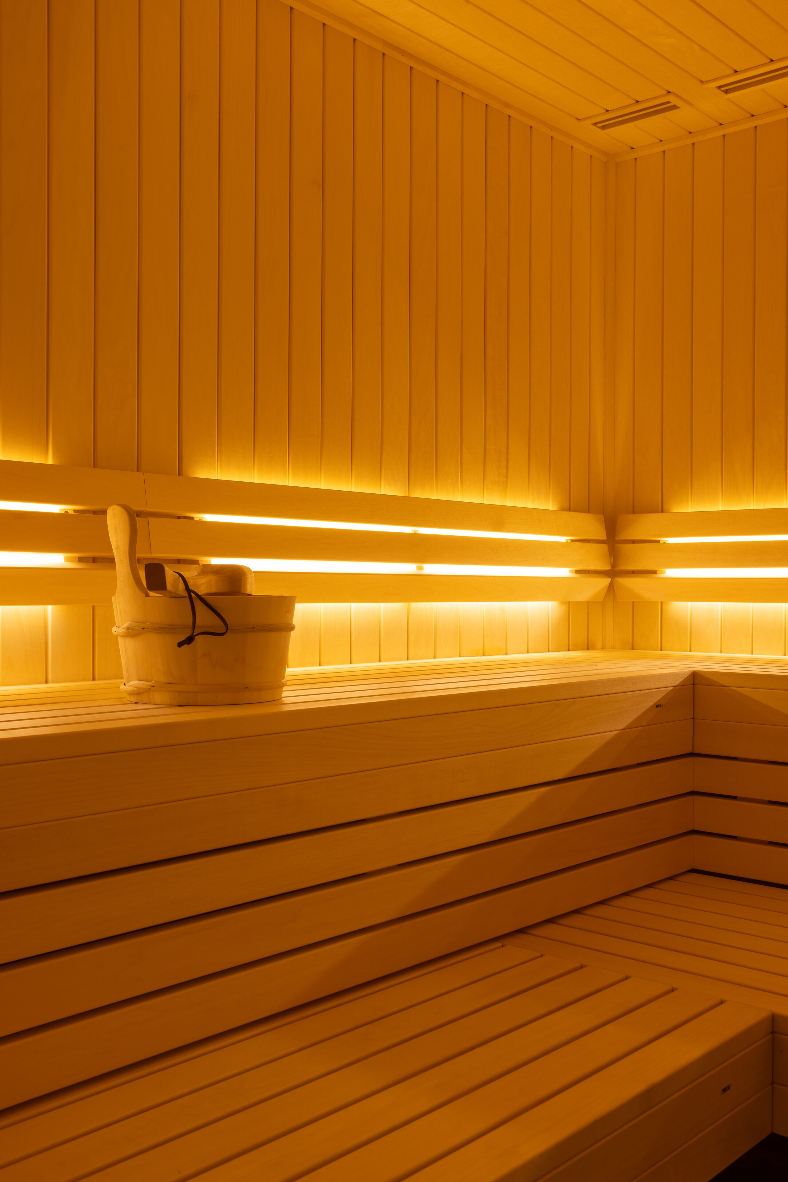 Una sauna con bancos de madera y un cubo.