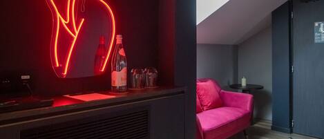A modern room with a neon art installation, a sofa, a small table, and a skylight.