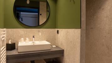 Een moderne badkamer met een ruime wastafel, spiegel en inloopdouche.