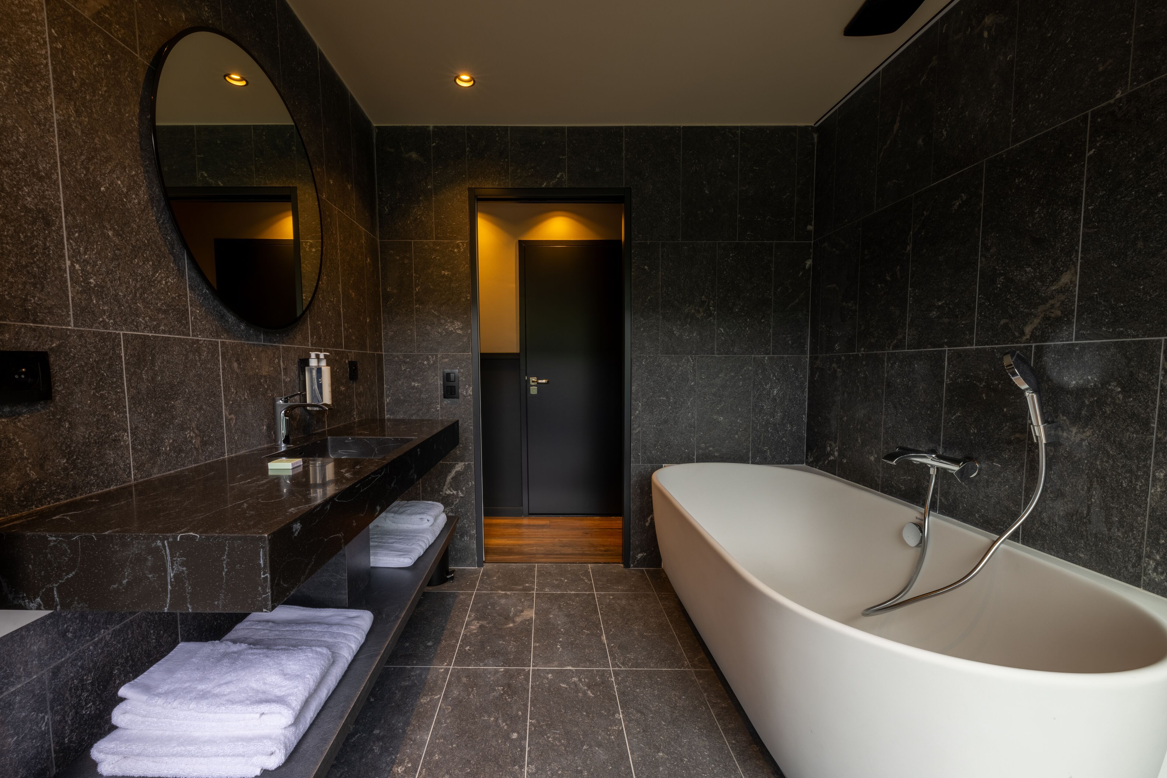 Une salle de bain moderne avec une baignoire sur pieds, un meuble-lavabo avec un miroir et un porte-serviettes.