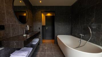 A modern bathroom with a freestanding bathtub, a vanity with a mirror, and a towel rack.