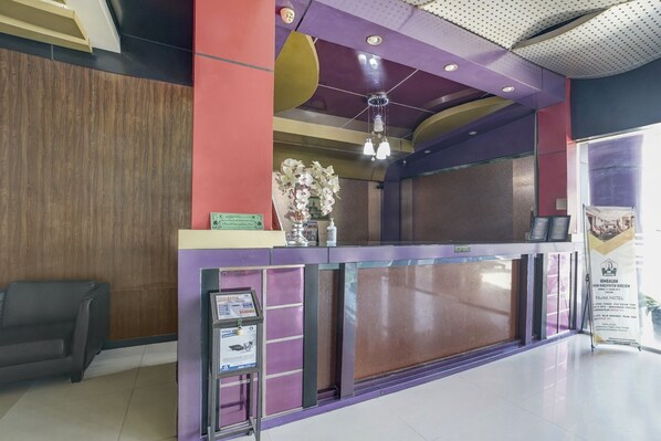A reception desk with a purple and brown color scheme, a wooden panel wall, and a black leather chair.