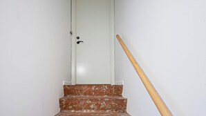A white door with a black handle, a wooden handrail, and a red and white marble staircase. - Charm 2 - Great 2-bdr Apt With Shared Garden and Balcony (Copenhagen)
