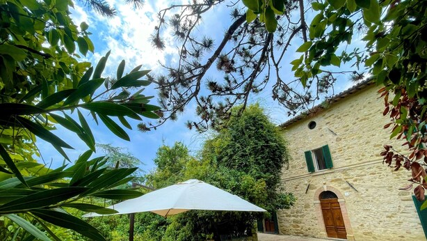 A patio with a table and chairs, a white umbrella, and a stone building with a window. - Umbrian Paradise Contains 5 Bedrooms With Private Pool and Stunning Views (Spoleto)