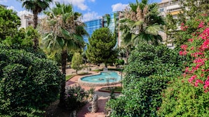 A landscaped area with a swimming pool, surrounded by palm trees and various shrubs. - Sanders Port - Trendy Studio Near Piraeus Port (Piraeus)