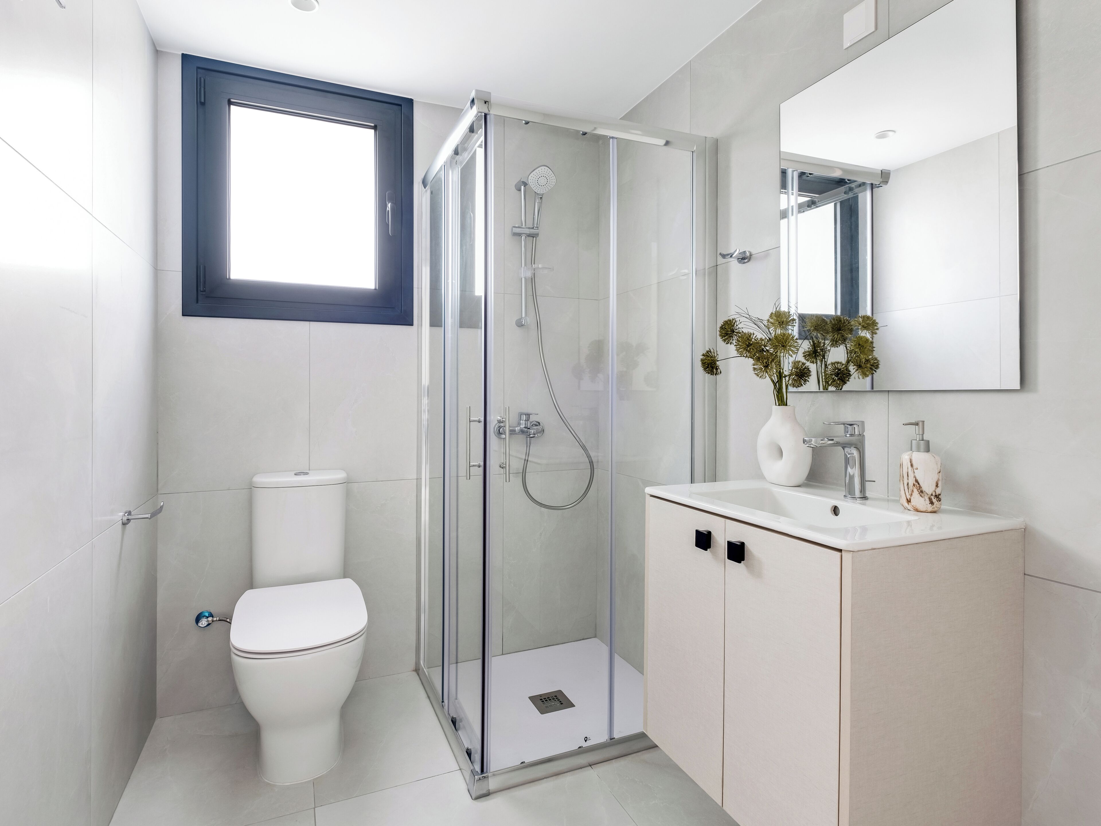 Een moderne badkamer met een glazen douchecabine, toilet en een wastafel met spiegel.